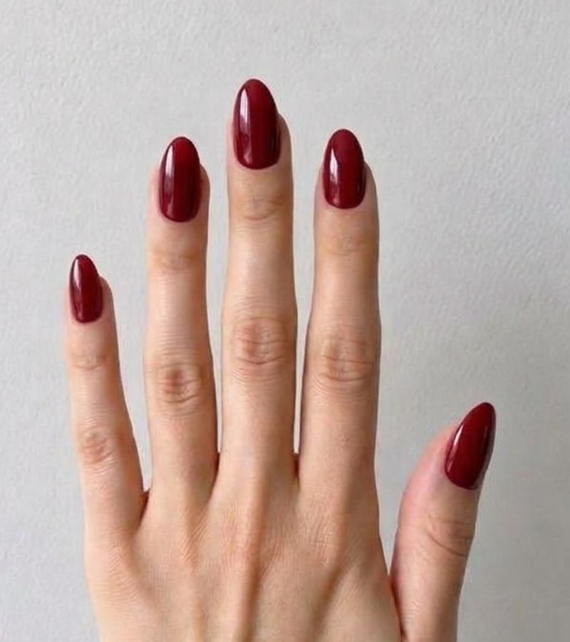 The same hand after a Nartie try-on: glossy cherry red almond nails