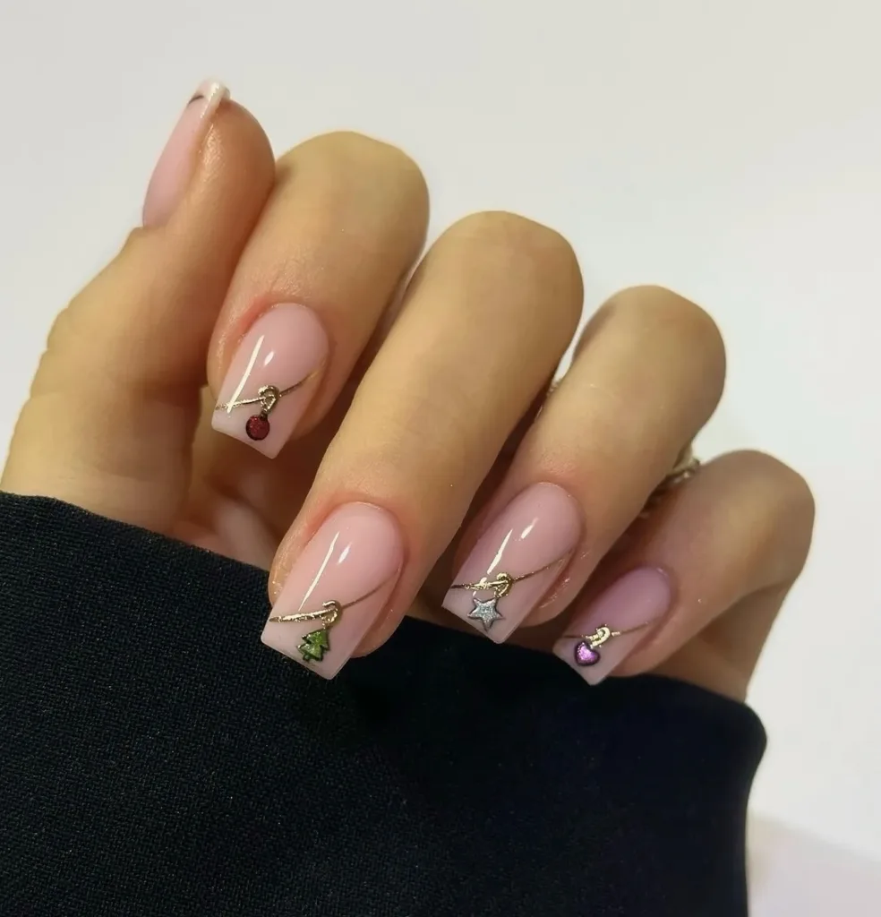 minimal pink christmas nails with gold chain and tiny festive charms