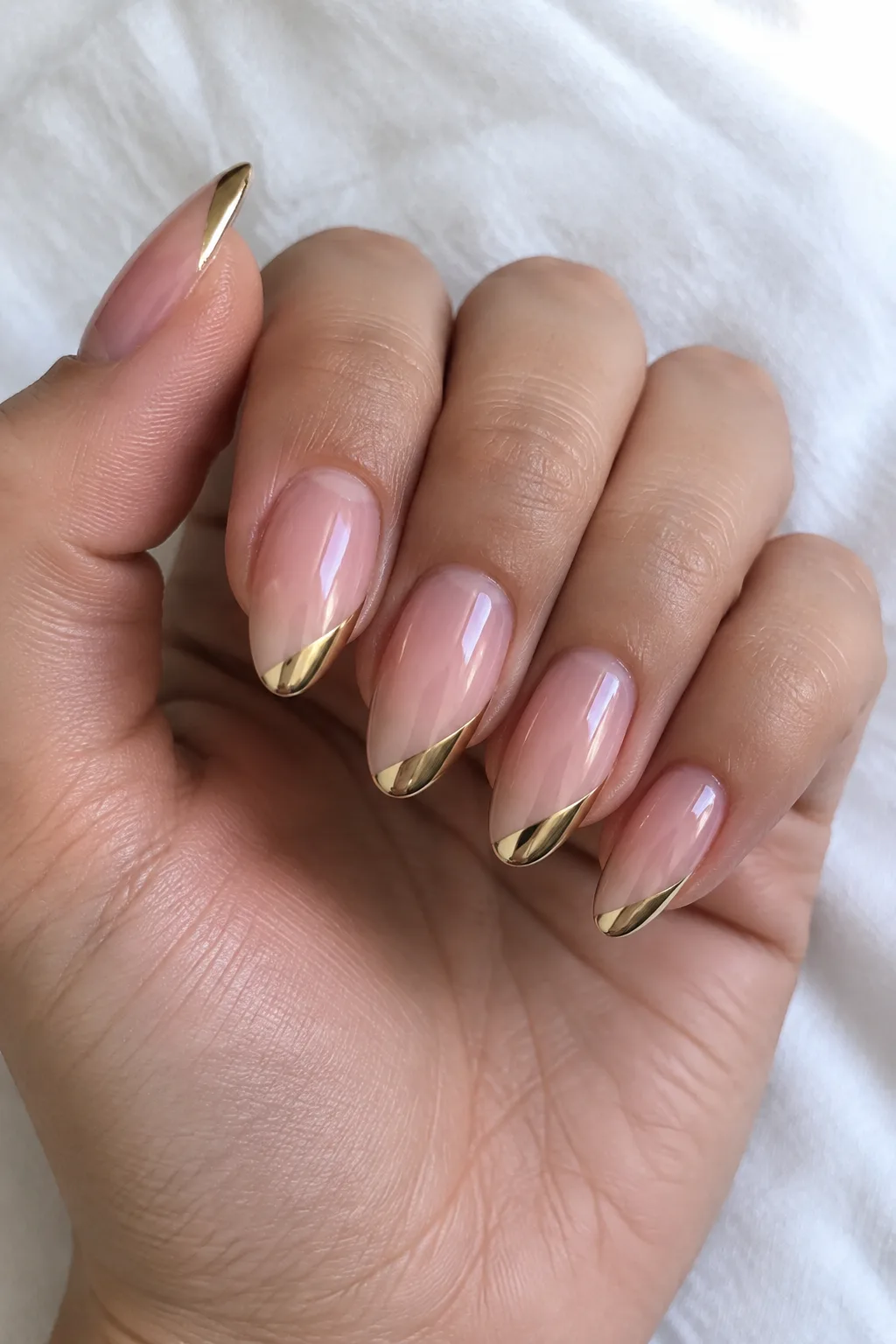 Sheer peach almond nails with slim diagonal gold french lines elongating short fingers