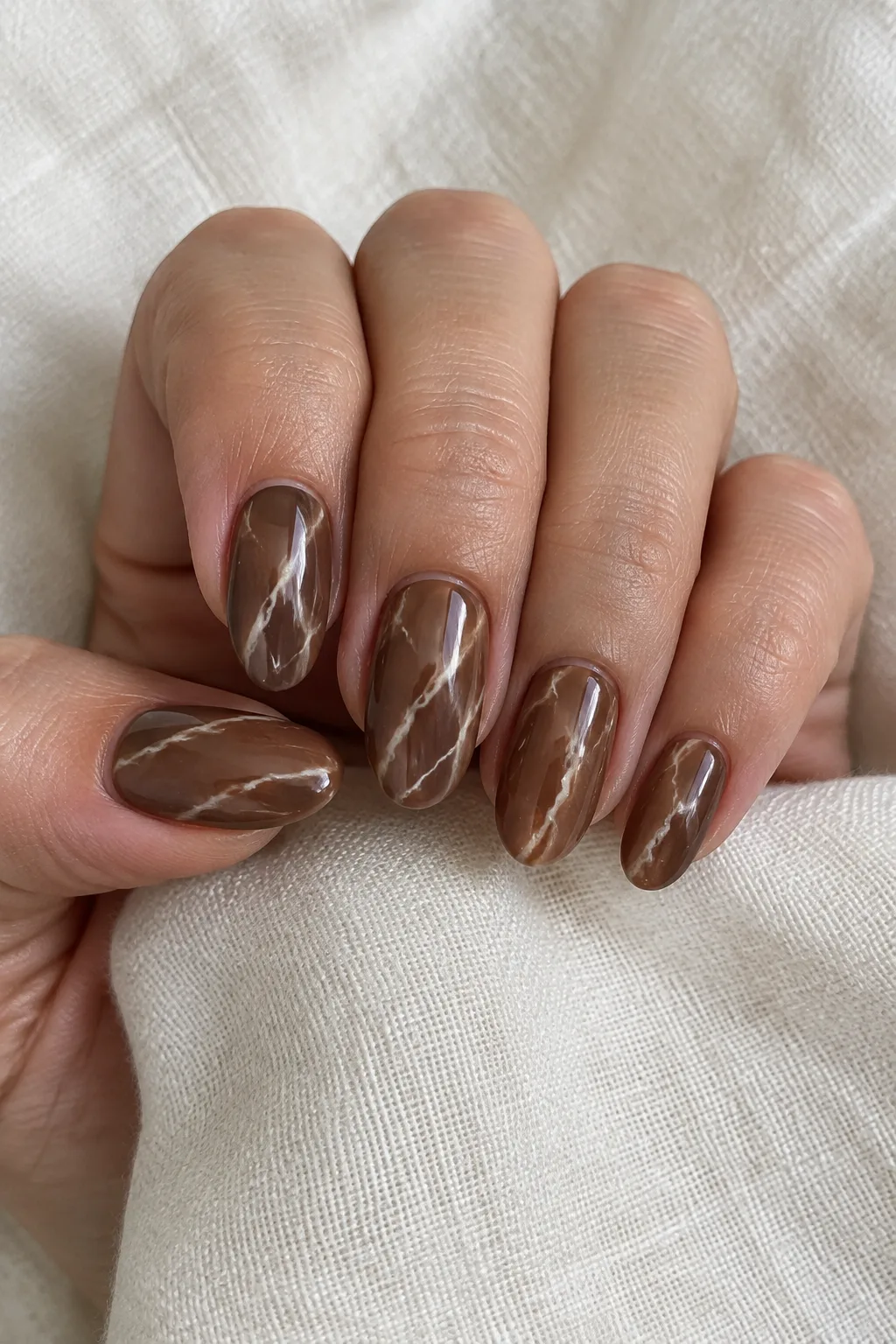 Chocolate brown marble almond nails with delicate cream vein detailing