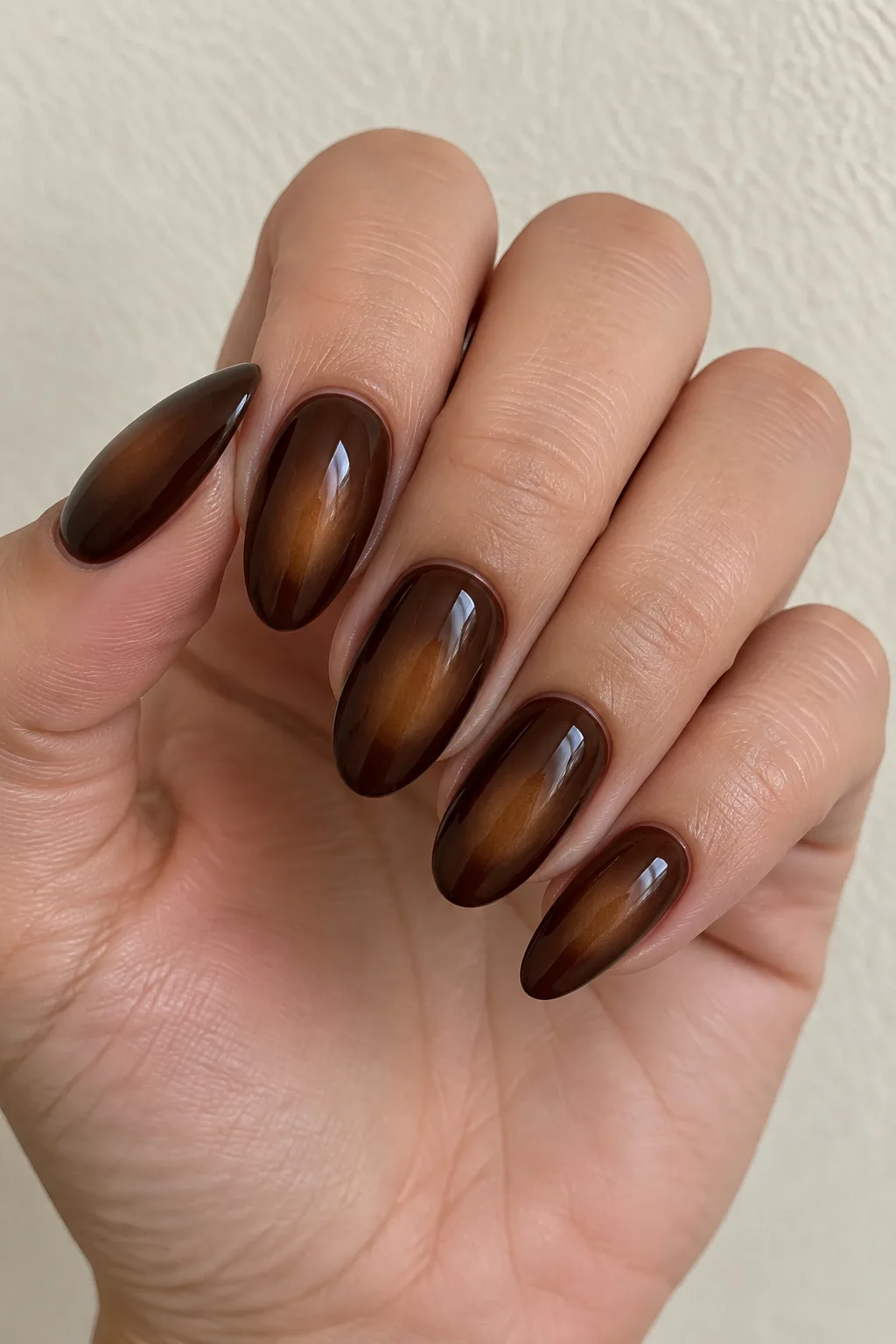 Chocolate aura almond nails with a soft caramel glow at the center