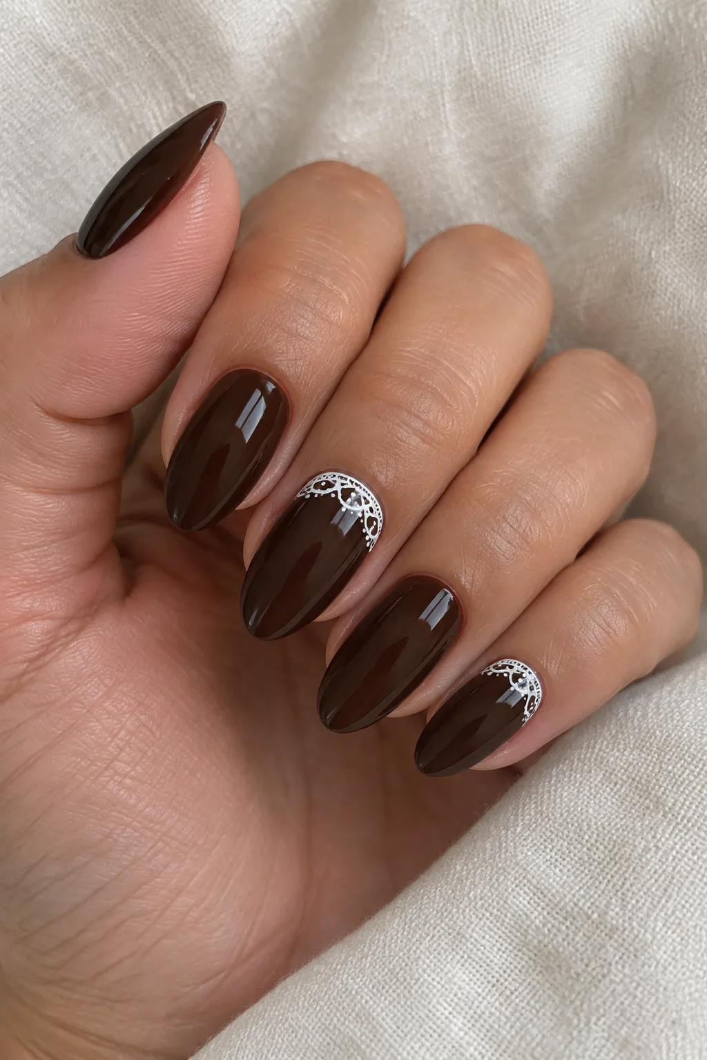 Espresso almond nails with fine white lace detailing at the cuticle
