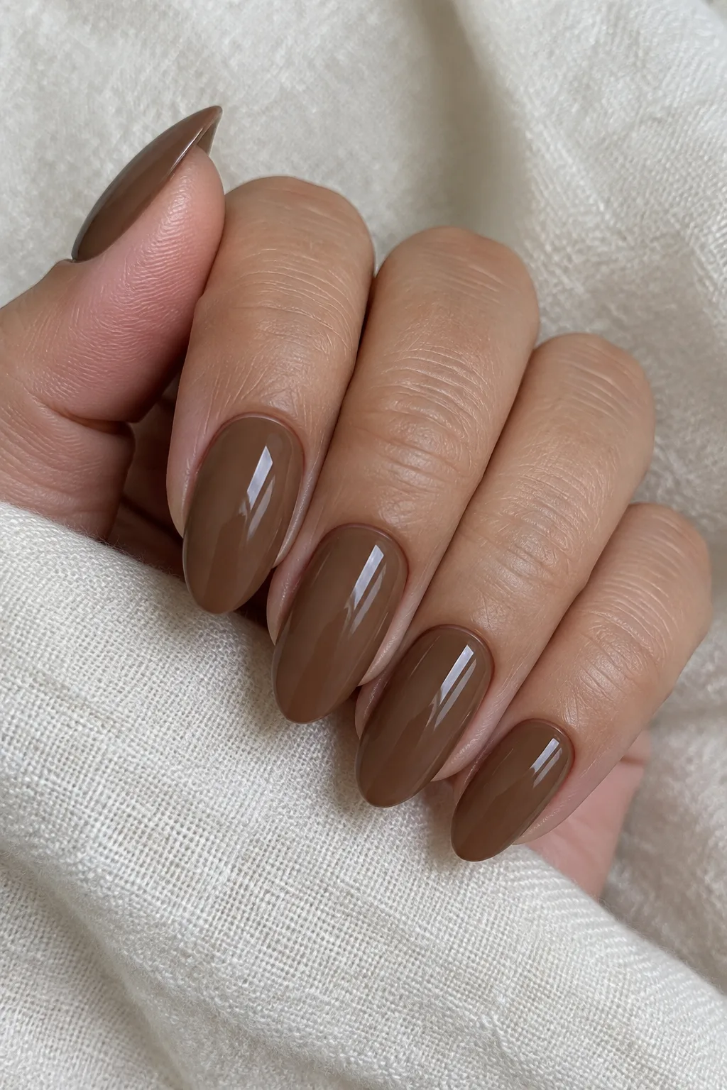 Milk chocolate brown almond nails painted in a smooth opaque cream finish