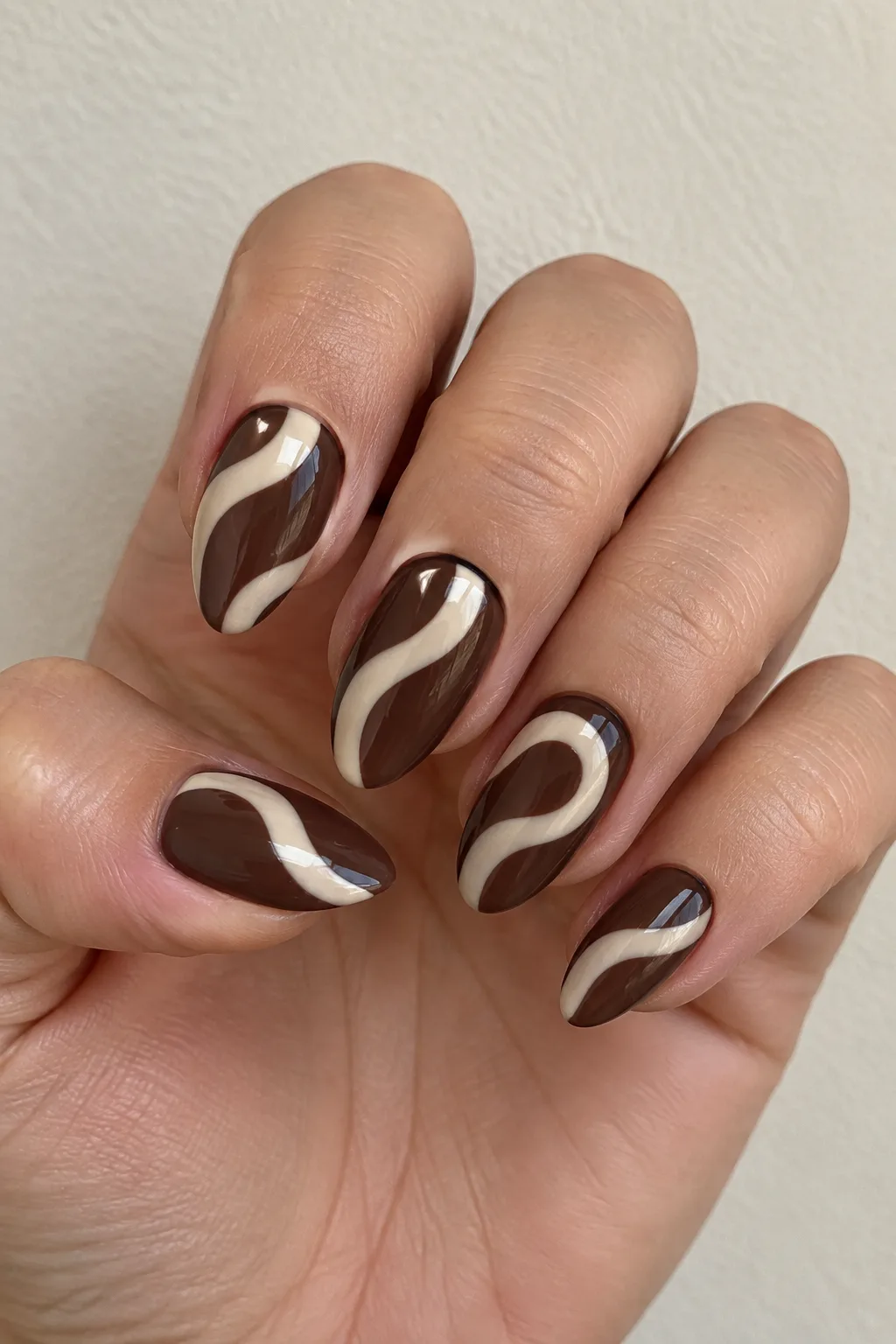 Chocolate brown almond nails with a swirled cream marble pattern