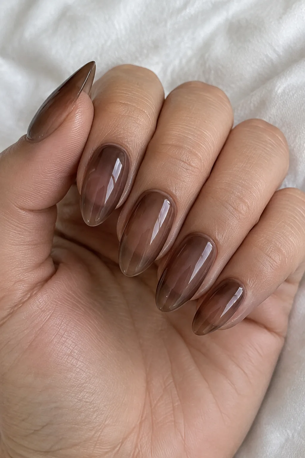 Sheer cocoa jelly almond nails with a translucent glass-like finish