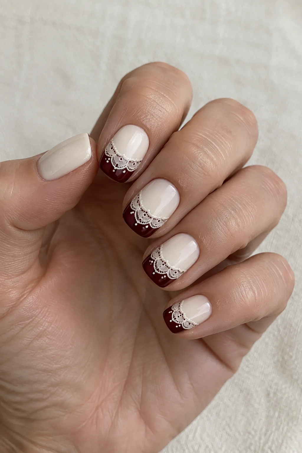 Burgundy lace pattern French tips on short edge shaped nails