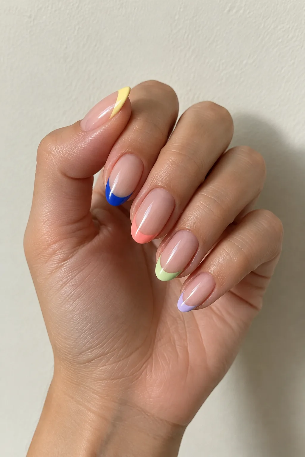 Five different colored French tips mixed across one set of almond nails