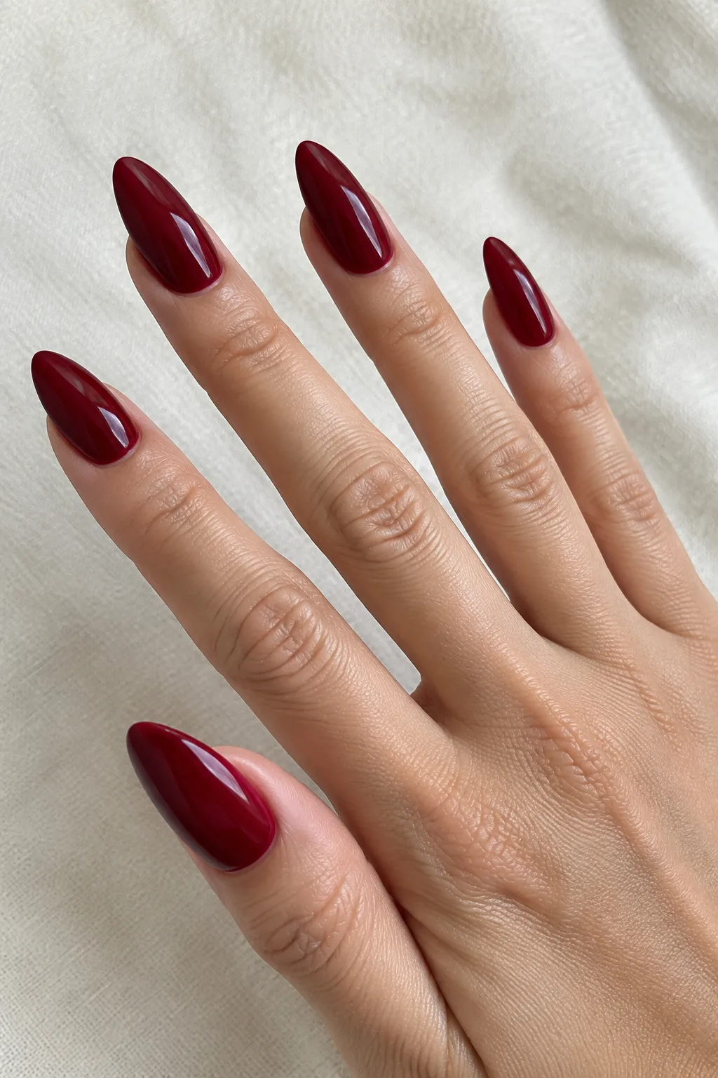 Long almond nails in cranberry red, a top fall nail color 2026