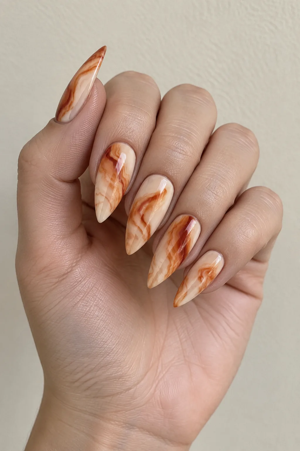 Burnt orange marble pattern on sharp stiletto nails with swirled veining