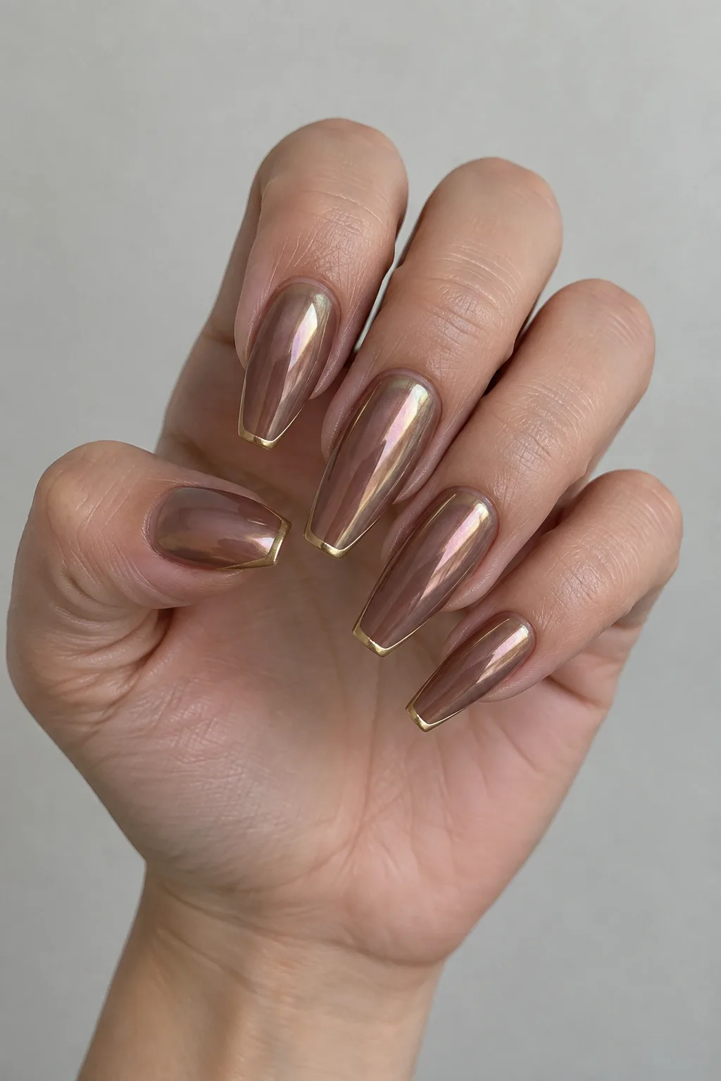 Cocoa brown glazed donut nails with pearl chrome powder and thin gold tip lines on coffin-shaped nails
