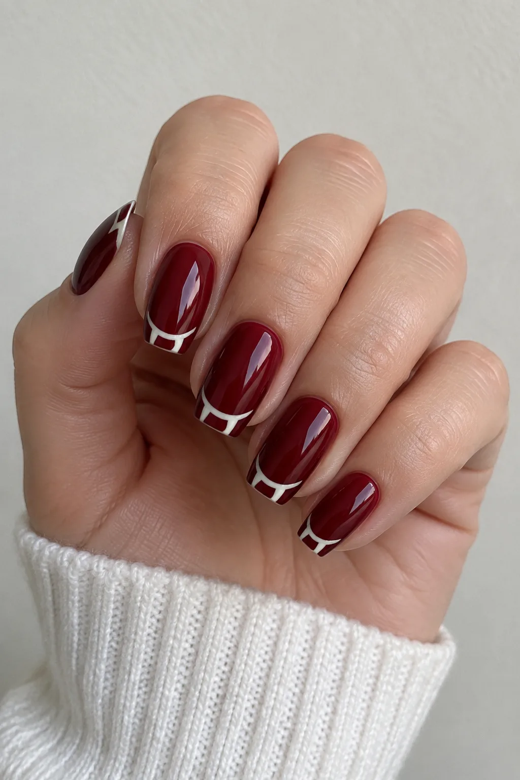 Deep wine red nails with a vampire fang-shaped smile line design