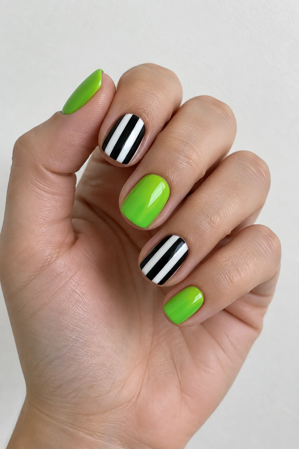 Black and white striped nails with acid green Beetlejuice-style accents