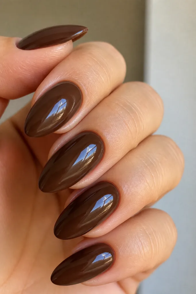 Long almond nails in glossy chocolate brown showing how to pick a nail shape for your hands