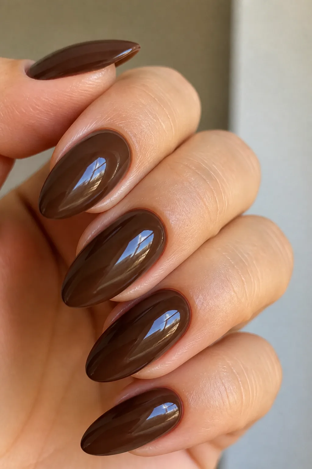Long almond nails in glossy chocolate brown showing how to pick a nail shape for your hands