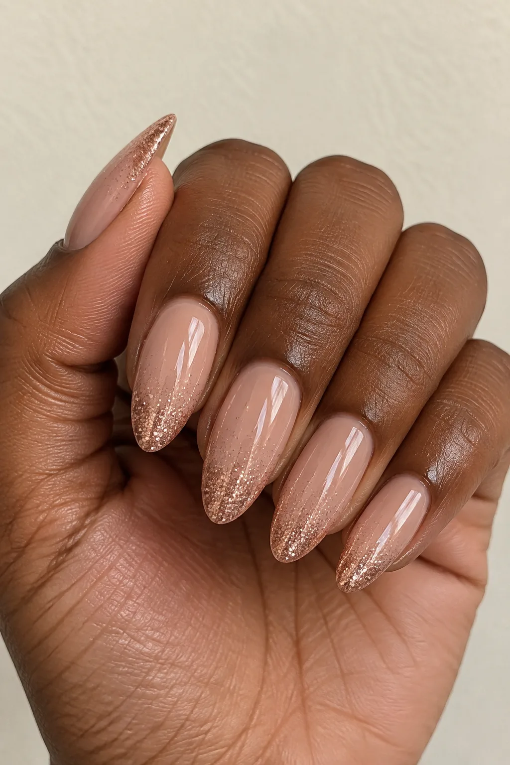 Caramel nude nails fading into rose gold glitter at the tips