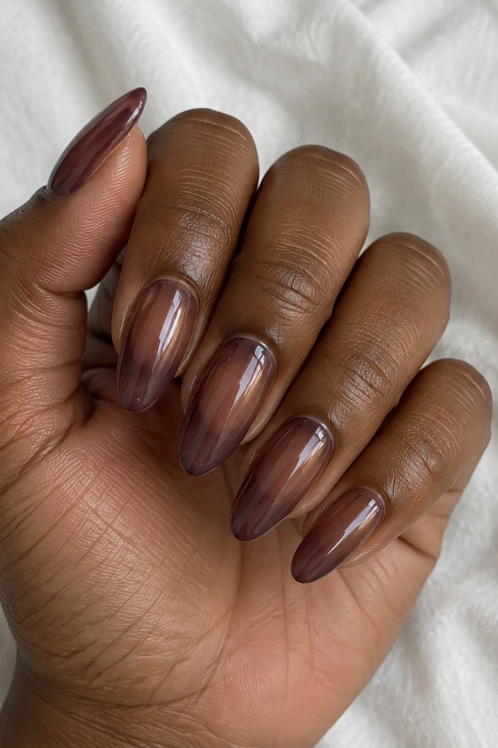 Sheer raisin-toned wash polish on long almond nails