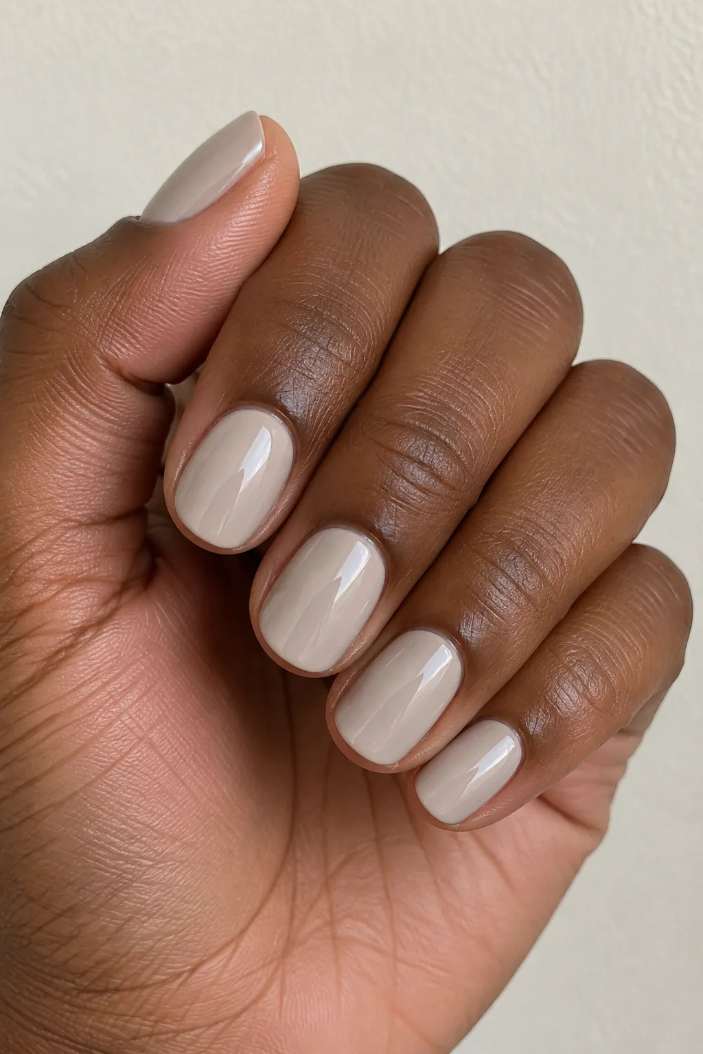 Sandy greige polish on short round nails with a soft matte look