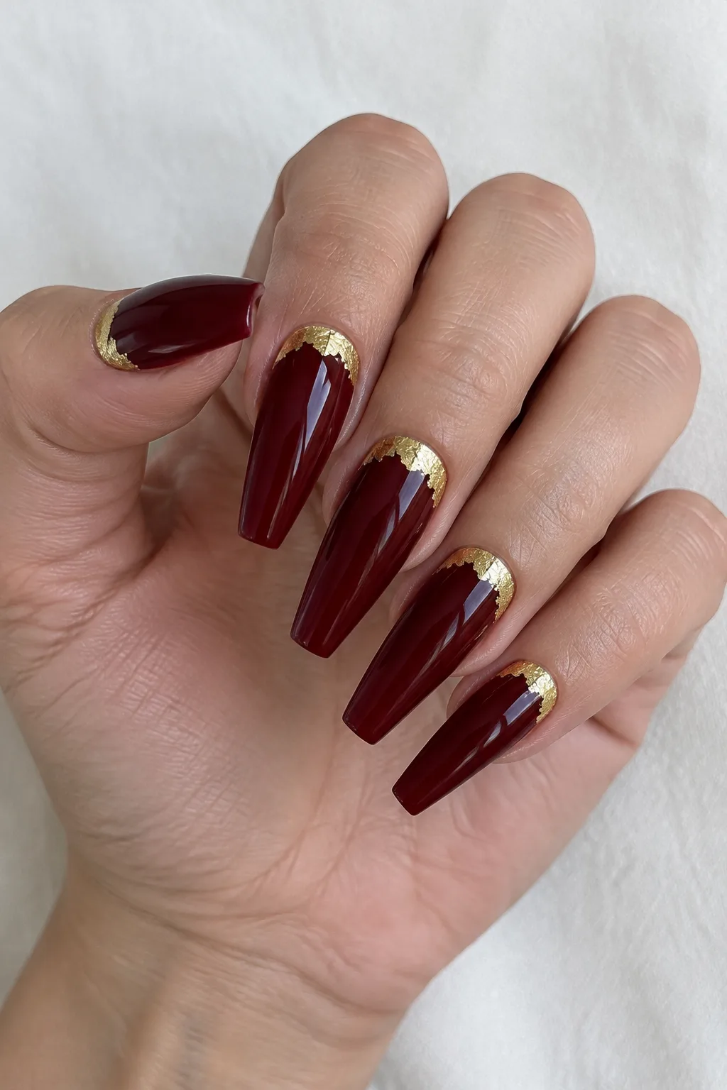 Long coffin nails in cranberry red with gold foil half-moon cuticles