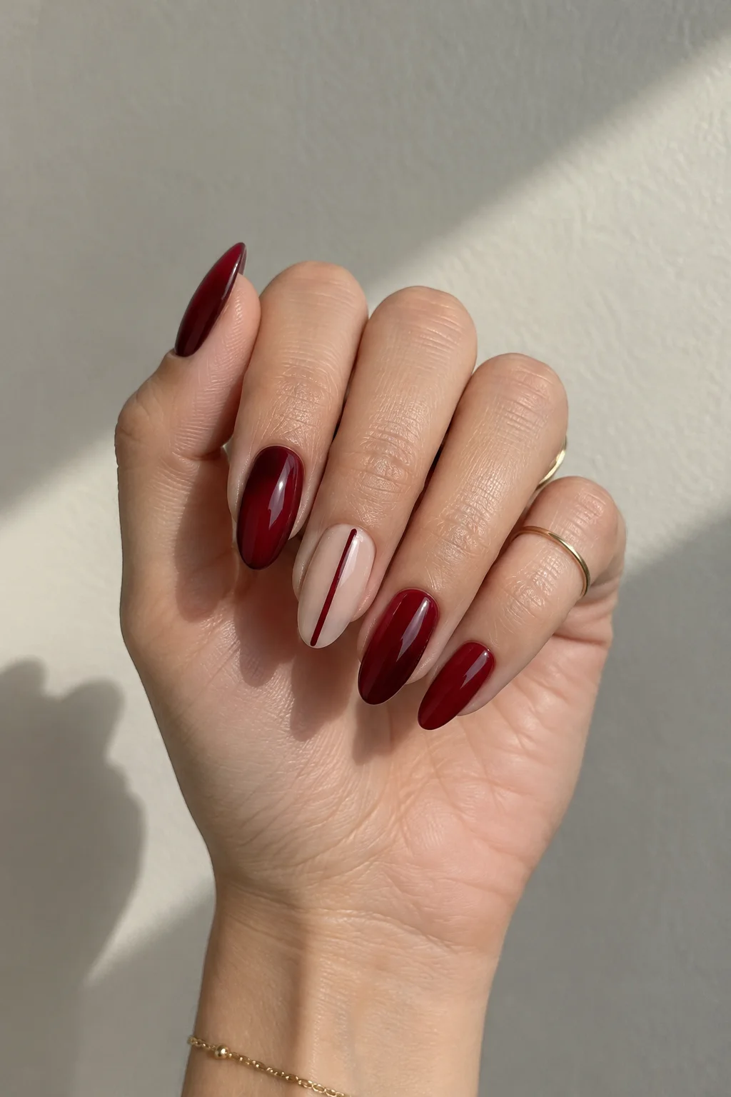 Oxblood nails with a vertical stripe that make wide nail beds look narrower