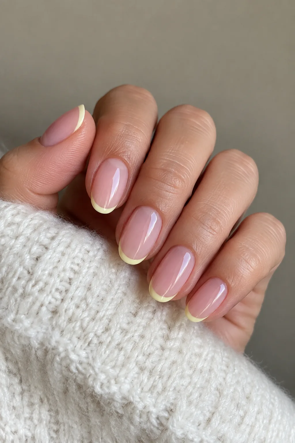 Butter yellow micro French tips on short almond nails with a sheer nude base