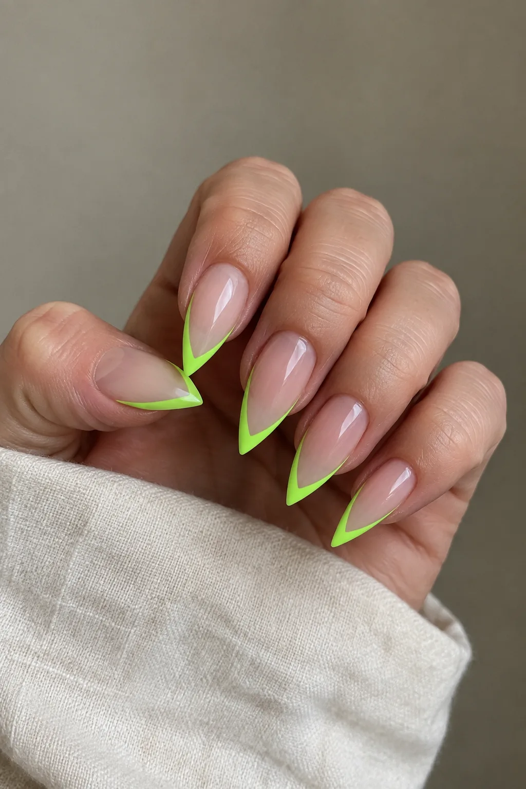Neon green outlined French tips on medium almond nails with a sheer base