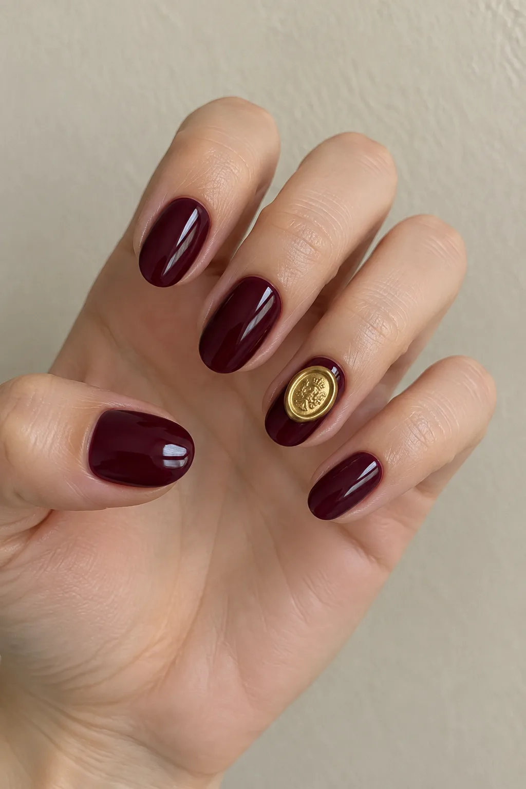 Gold wax seal accent on wine dark red fall nails, round shape