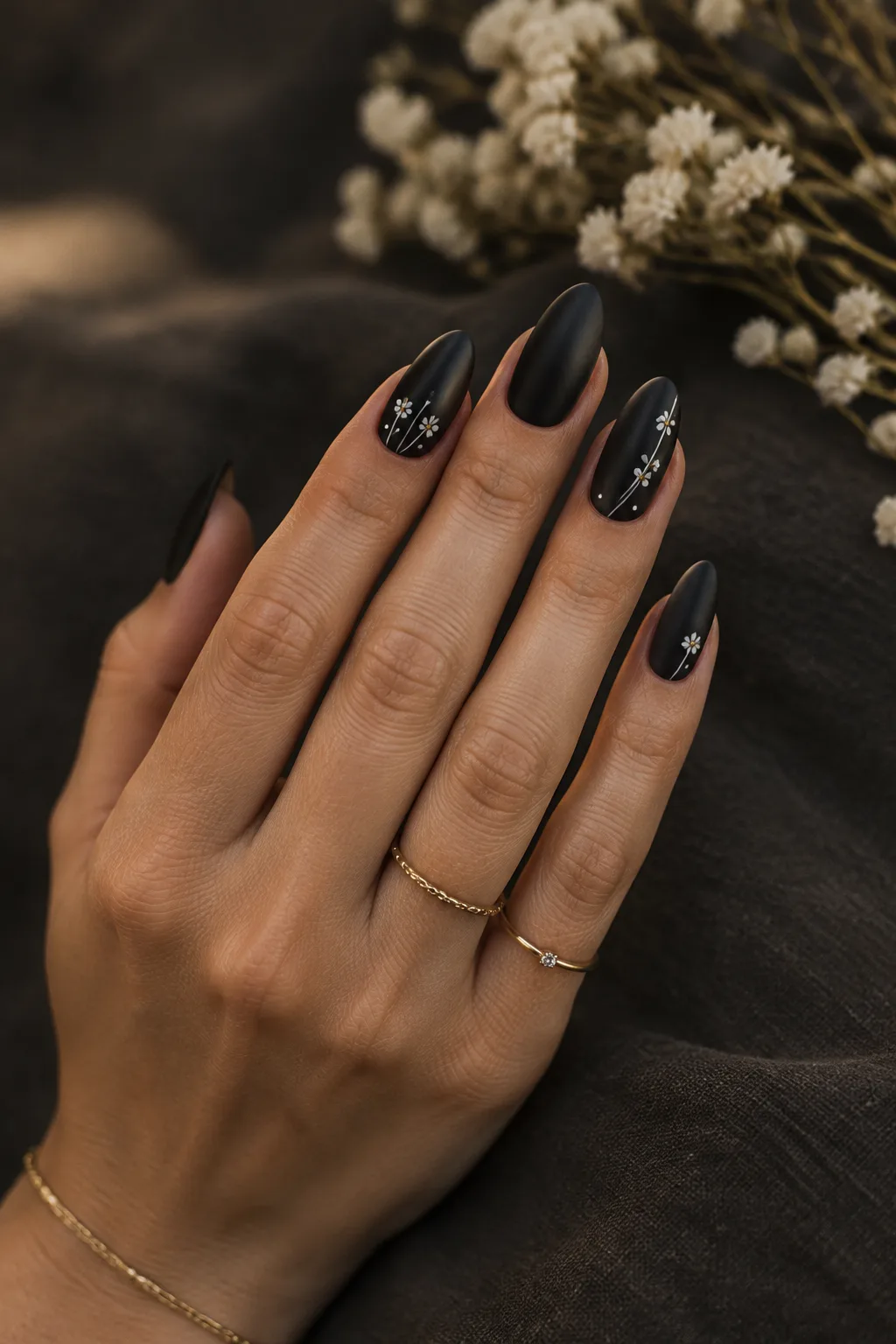 Matte black almond nails with white fine-line wildflowers