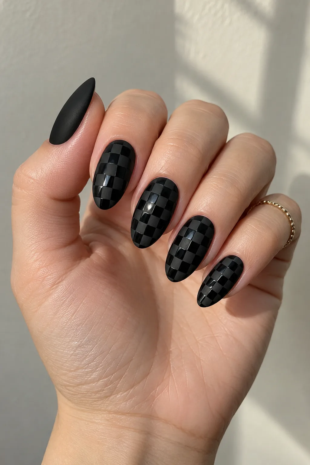Matte black almond nail design with a subtle black-on-black checkerboard texture