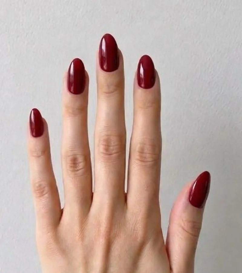 The same hand after a Nartie try-on: glossy cherry red almond nails