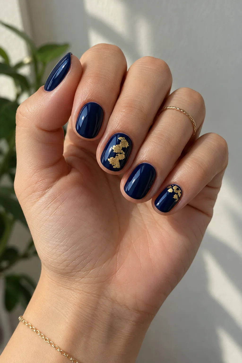 Short Christmas nails with deep navy polish and torn gold foil accents