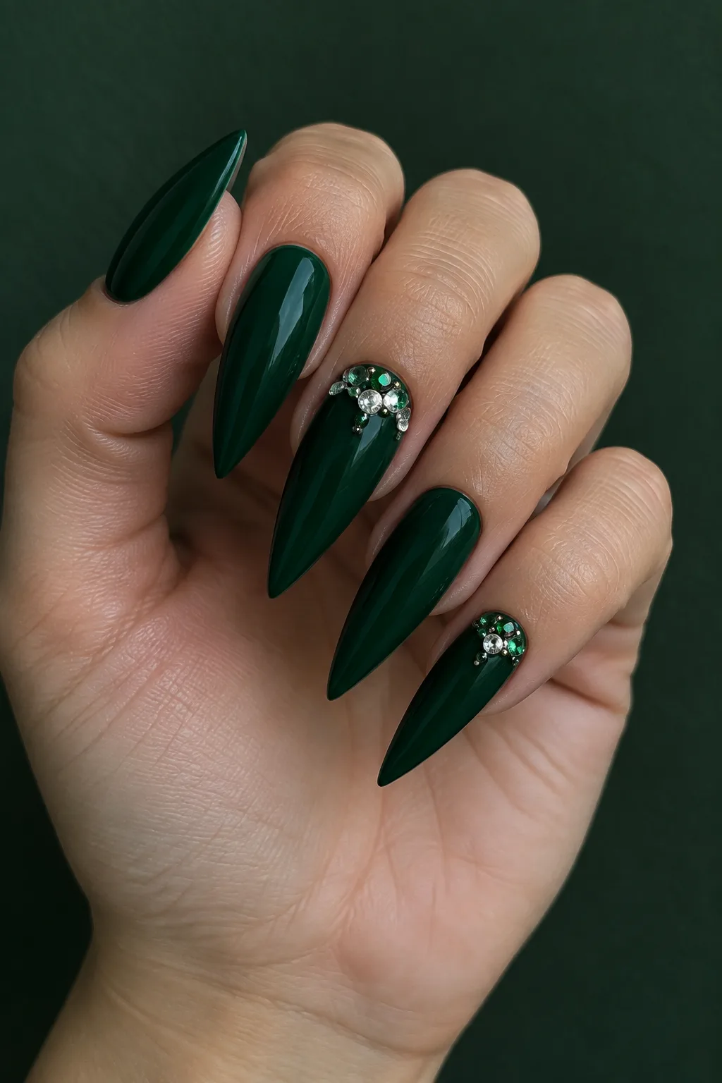 Emerald green stiletto nail designs with a crystal cluster accent
