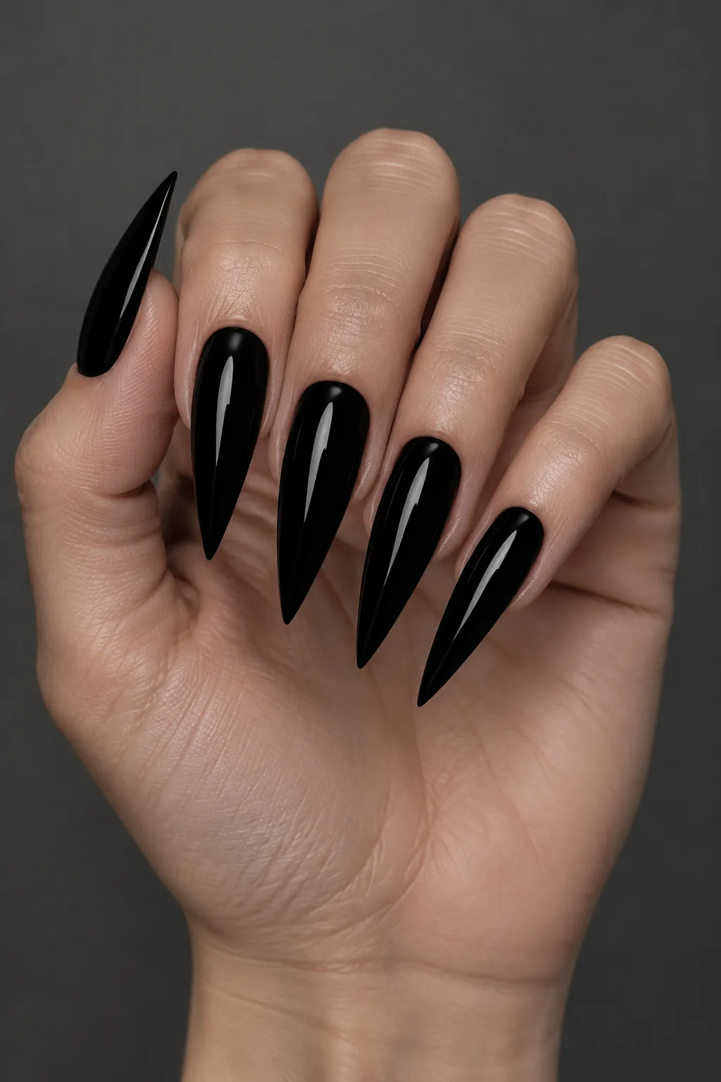 Glossy black stiletto nail design with long sharp wet-look tips