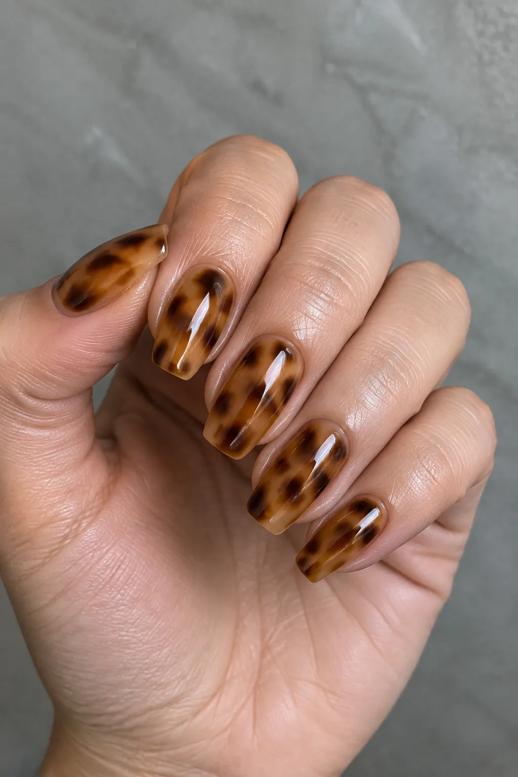 Amber and brown tortoiseshell pattern painted on short coffin-shaped nails