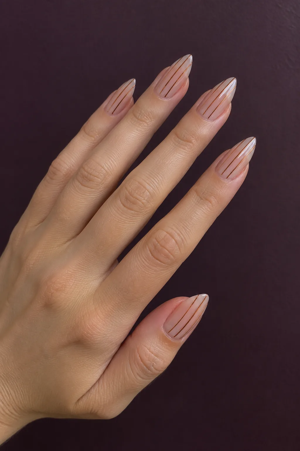 Thin copper pinstripes over a nude base on short arrowhead-shaped nails