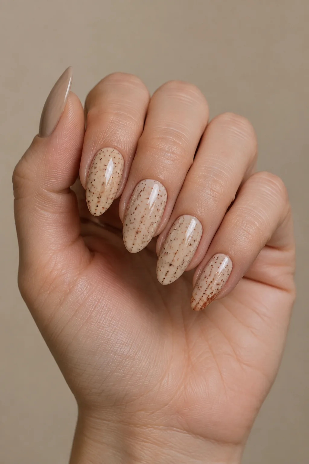 Sand beige angled lipstick tip nails with a nutmeg speckle pattern
