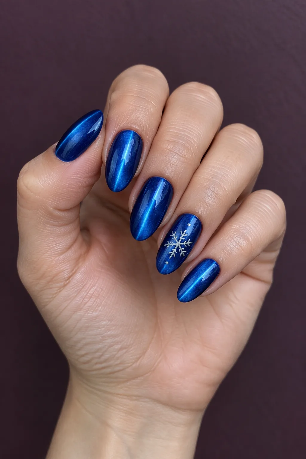 Velvet nails winter ideas in sapphire blue magnetic gel with a silver snowflake accent nail